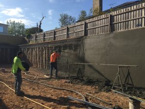 Man applying shotcrete to a below ground foundation wall of a residential project